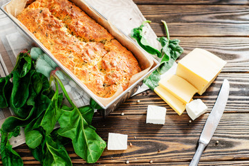 baked cheese pie with spinach , feta and fresh ingredients on a wooden background