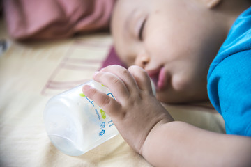 Obraz na płótnie Canvas closeup Baby hand and finger . Baby holding bottle while sleep