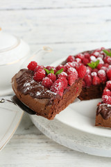 Piece of cake with chocolate Glaze and raspberries on color wooden background