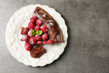 Piece of cake with Chocolate Glaze and raspberries on plate on dark background