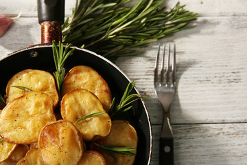 Delicious baked potato with rosemary in frying pan on table close up