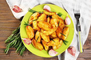 Baked potato wedges on wooden table, top view