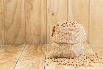 Fototapeta premium Soy beans in sack on wooden desk
