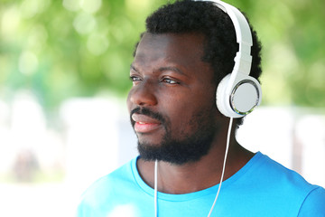 African American man listening music with headphones on blurred background