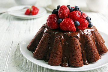 Delicious chocolate cake with strawberries in plate on table, closeup