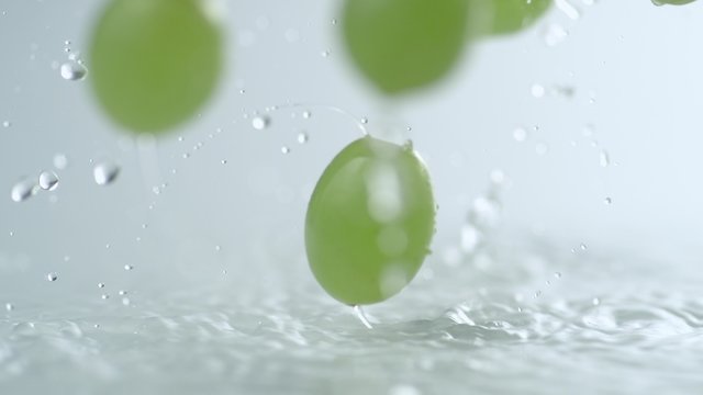 Green grapes falling and bouncing on water surface. Shot with high speed camera, phantom flex 4K. Slow Motion. 