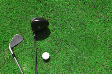 Golf clubs and ball on a green grass