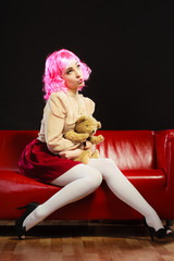 childlike woman and teddy bear sitting on couch