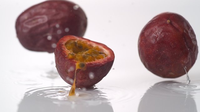 Passion fruit falling and bouncing on water surface. Shot with high speed camera, phantom flex 4K.  Slow Motion. 