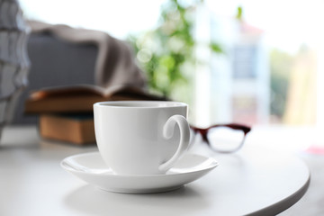 Cup of coffee with books on table in room