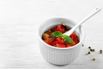 Tasty vegetarian ratatouille made of eggplants, squash, tomatoes in bowl on wooden table background