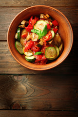 Tasty vegetarian ratatouille made of eggplants, squash, tomatoes in bowl on wooden table background