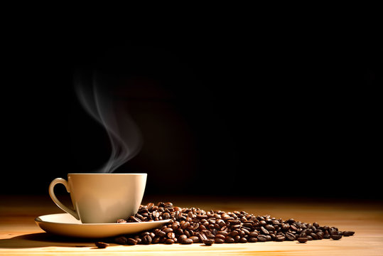 Fototapeta Cup of coffee with smoke and coffee beans on old wooden background
