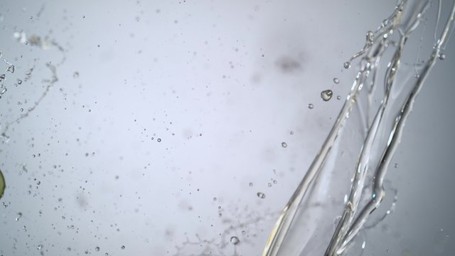 Cut avocado colliding against oil stream. Shot with high speed camera, phantom flex 4K. Slow Motion.