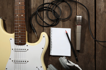Electric guitar with headphones and microphone on wooden background