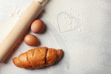 Hearts of flour and rolling pin on light background