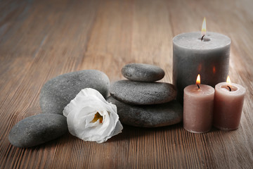 Aroma candle with pebbles and flower  on wooden background