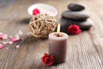 Beautiful composition of aroma candle with pebbles and flower  on wooden background