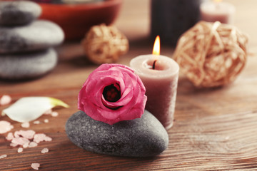 Fototapeta na wymiar Beautiful composition of aroma candle with pebbles and flower on wooden background