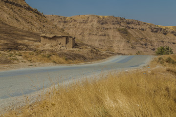 Iraqi countryside in autumn season showing paved street with small shelter on the side of the road used by shepherds and famers in that area
