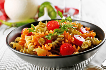 Delicious macaroni dish in black bowl on served grey wooden table
