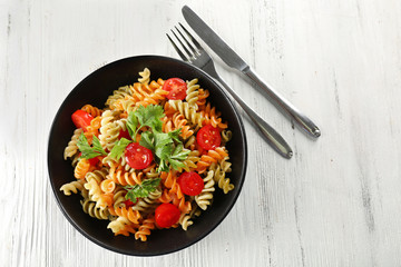 Delicious macaroni dish in black bowl on served grey wooden table