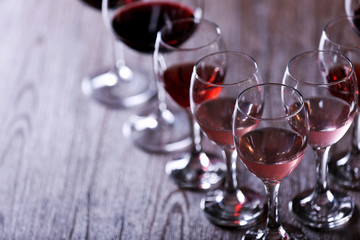 Wineglasses with white, red and pink wine on wooden table close-up