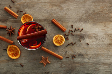 Mulled wine with spices on wooden background