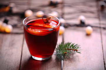 Mulled wine with spices and Christmas tree on wooden background