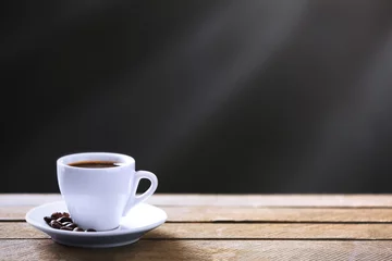 Foto op Plexiglas Kopje koffie en koffiebonen op houten tafel, op grijze achtergrond © Africa Studio