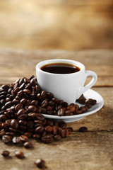 Cup of coffee and coffee grains on wooden background