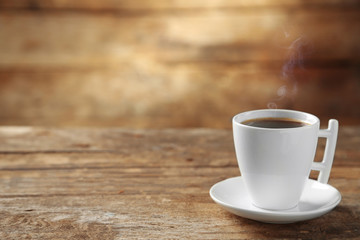 Cup of coffee and coffee grains on wooden background