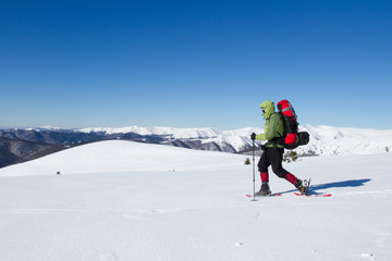 Hiker in winter mountains snowshoeing.