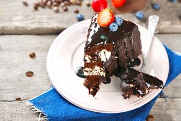 Chocolate cake with cream and fresh berries on plate, on wooden background