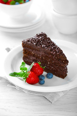 Chocolate cake with chocolate cream and fresh berries on plate, on light background
