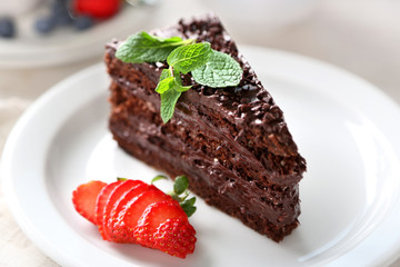 Chocolate cake with chocolate cream and fresh berries on plate, on light background