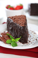 Chocolate cake with chocolate cream on plate, on light background