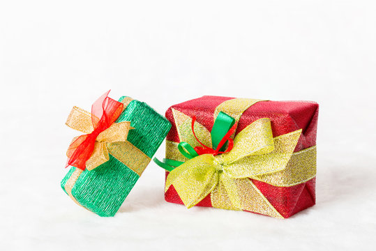Red and green Christmas gift box with shiny golden ribbon on white background.