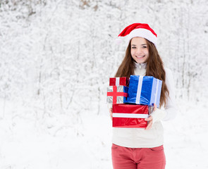 teen girl with santa hat and red gift boxes standing in winter f