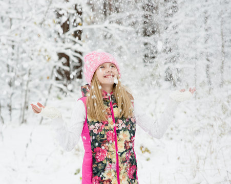 girl in winter forest enjoying snowfall
