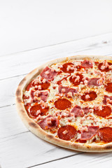 Delicious fresh pizza with sausage ham salami served on wooden table
