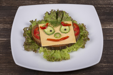 Face on bread, made from lettuce, tomato, cucumber and pepper.