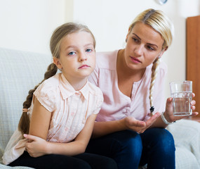 Little girl with pain in belly and worried mother indoors