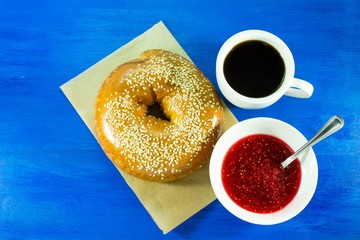 Fresh bagel with sesame seeds, jam and coffee