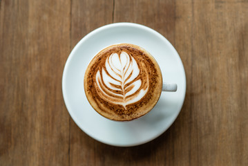 selective focus of latte art served on white cup and wooden background