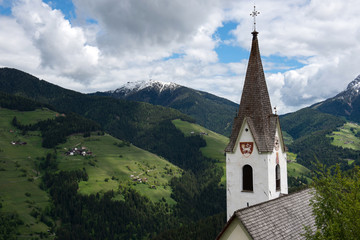 Fototapeta na wymiar Kirchturm von Enneberg mit Almwiesen, Südtirol, Italien
