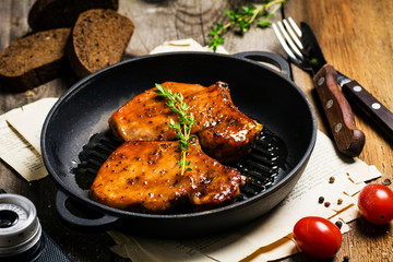 BBQ pork chops in sweet honey and pepper glaze on iron skillet, close up