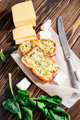 
baked cheese pie with spinach , feta and fresh ingredients on a wooden background