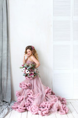Romantic fashion woman in a pink dress and bouquet.