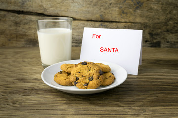 cookies and a glass with milk with a white note for santa